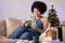 African american Woman buying with credit card and cell phone. Black woman celebrating holiday festivities at home