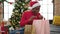 African american woman celebrating christmas looking shopping bags at home