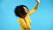 African american woman dancing with headphones on blue background. Girl gets high because of music track. Radio