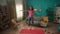 African American woman doing star jumping on a gym mat in the living room. A slender girl takes care of her health