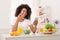 African-american woman eating healthy salad and using smartphone