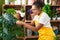 African american woman florist smiling confident touching sheet plant at flower shop