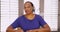 An African American woman has joint and muscle pain while talking to the camera at home