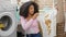 African american woman holding dirty shirt looking upset at laundry room