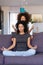 African American woman with little daughter practicing yoga at home