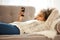African american woman lying on sofa and looking on mobile phone
