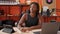 African american woman musician writing on paperwork composing song at music studio