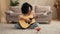 African American woman plays an acoustic guitar, sings song and talks on video call using smartphone. Black brunette