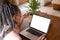 African american woman spending time in log cabin and having laptop video call with copy space