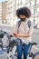 African-American woman using her smart phone to pay for a bicycle rental. Eco-friendly transportation concept