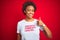 African american woman wearing sarcastic comments t-shirt over red isolated background doing happy thumbs up gesture with hand