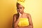 African american woman wearing towel after shower standing over  yellow background thinking looking tired and bored with