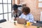 African american women business workers using laptop writing on paperwork at office