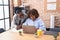 African american women business workers using laptop writing on paperwork at office