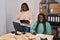 African american women ecommerce business workers talking on smartphone writing on notebook at office