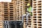 African American worker in safety vest suit and hardhat using mobile phone to check the incoming cargo while sitting on the pallet