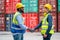 African American worker or technician shake hands with Asian staff in cargo container workplace area with stack of container tank