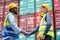 African American worker or technician shake hands with Asian staff in cargo container workplace area with stack of container tank