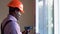 African american workman in overalls installing or adjusting plastic windows in the living room at home