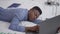 African American young businessman falling asleep lying on bed with laptop. Portrait of overburdened overworked handsome