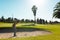 African american young man hitting golf shot with club against clear sky at golf course in summer