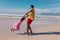 African american young man holding daughter\'s hands and spinning her at beach against blue sky