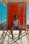 African american young man looking away while sitting on lifeguard hut at beach on sunny day