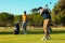 African american young man standing while caucasian friend hitting with golf club at golf course