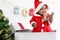 African baby kid in Santa Claus red costume standing in big gift box present at white room, beautiful little child celebrates