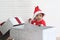 African baby kid in Santa Claus red costume stands near big gift box present at white room, beautiful little child celebrates