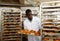 African baker placing tray with baked rolls on trolley