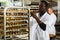 African baker putting tray with bakery goods on trolley