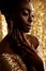 African Beauty Woman with Gold Jewelry over shining Background. Dark Skinned Model with Golden Lips Make up Profile. Afro Fashion
