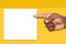 African, Black Man`s Hand Pointing at a Blank Sign on a Mustard Yellow Background