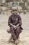 African boy sitting on wooden bench and looking at camera with blurred background