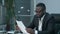African Businessman doing paper work, calculating finance bills in office