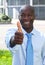 African businessman in front of his office showing thumb