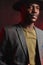 African businessman in grey suit and black hat in studio on dark background