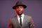 African businessman in grey suit and black hat in studio on dark background