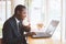 African Businessman  holding coffee with smile and playing labtop