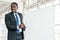 African businessman presents and listens to opinions at a business group meeting with empty whiteboard.