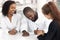 African businessman sitting at desk with diverse workers signing contract