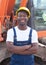 African construction worker with crossed arms and red excavator