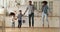 African couple and children holding hands jumping in modern kitchen