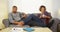 African couple using electronic devices on couch