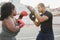 African curvy woman and personal trainer doing boxing workout session outdoor - Focus on left girl arm
