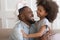 African daughter holding rabbit soft toy playing with father indoors