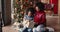 African daughter and mom sit on floor near Christmas tree