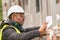 African engineer checking office blueprints on construction site