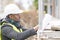 African engineer checking office blueprints on construction site